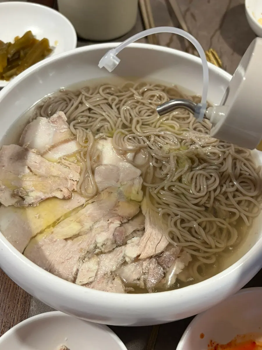 Naengmyeon noodles lifted with chopsticks