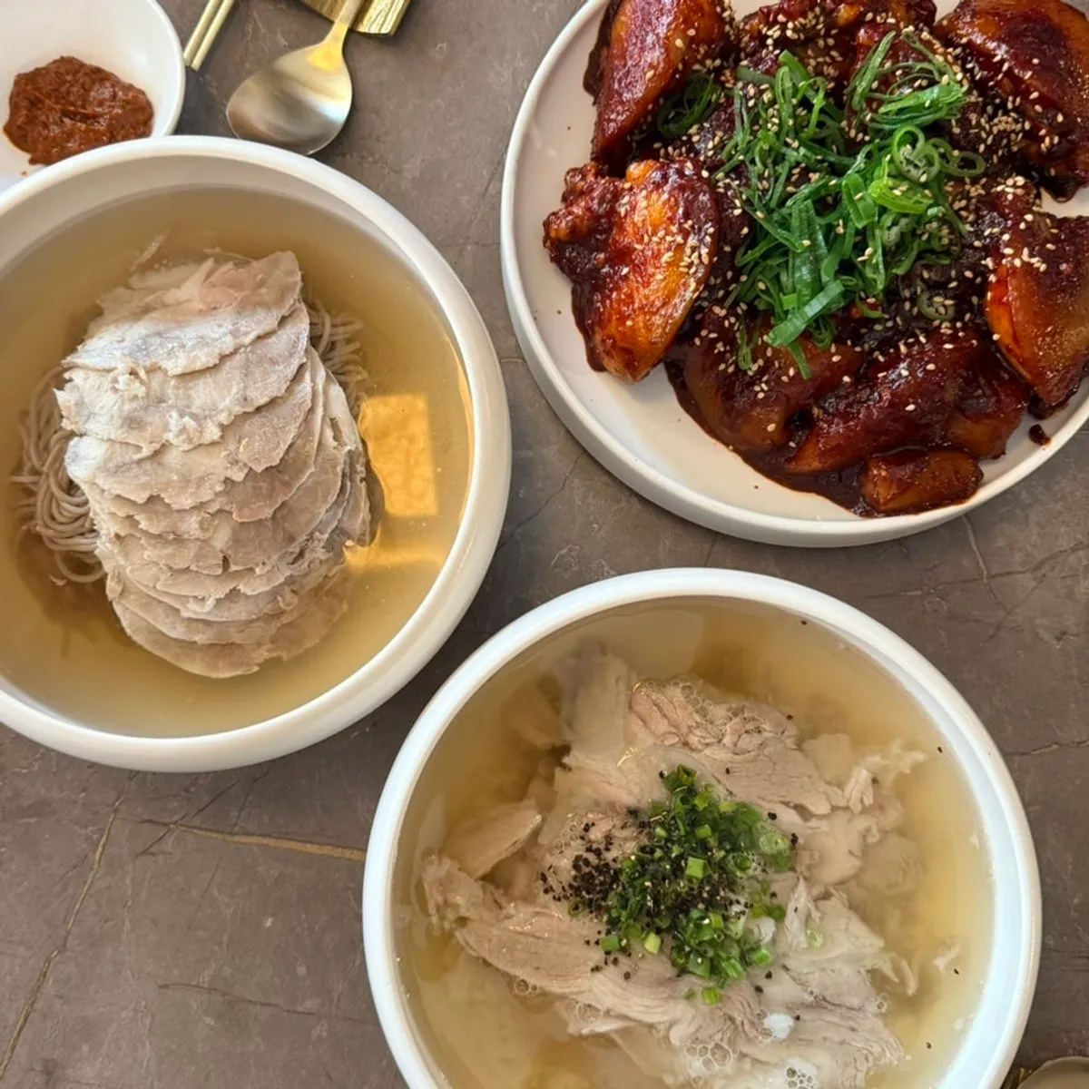 All three dishes — naengmyeon, gomtang, pork tail jjim — laid out together