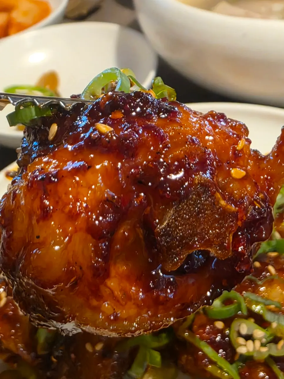 A piece of pork tail lifted with chopsticks