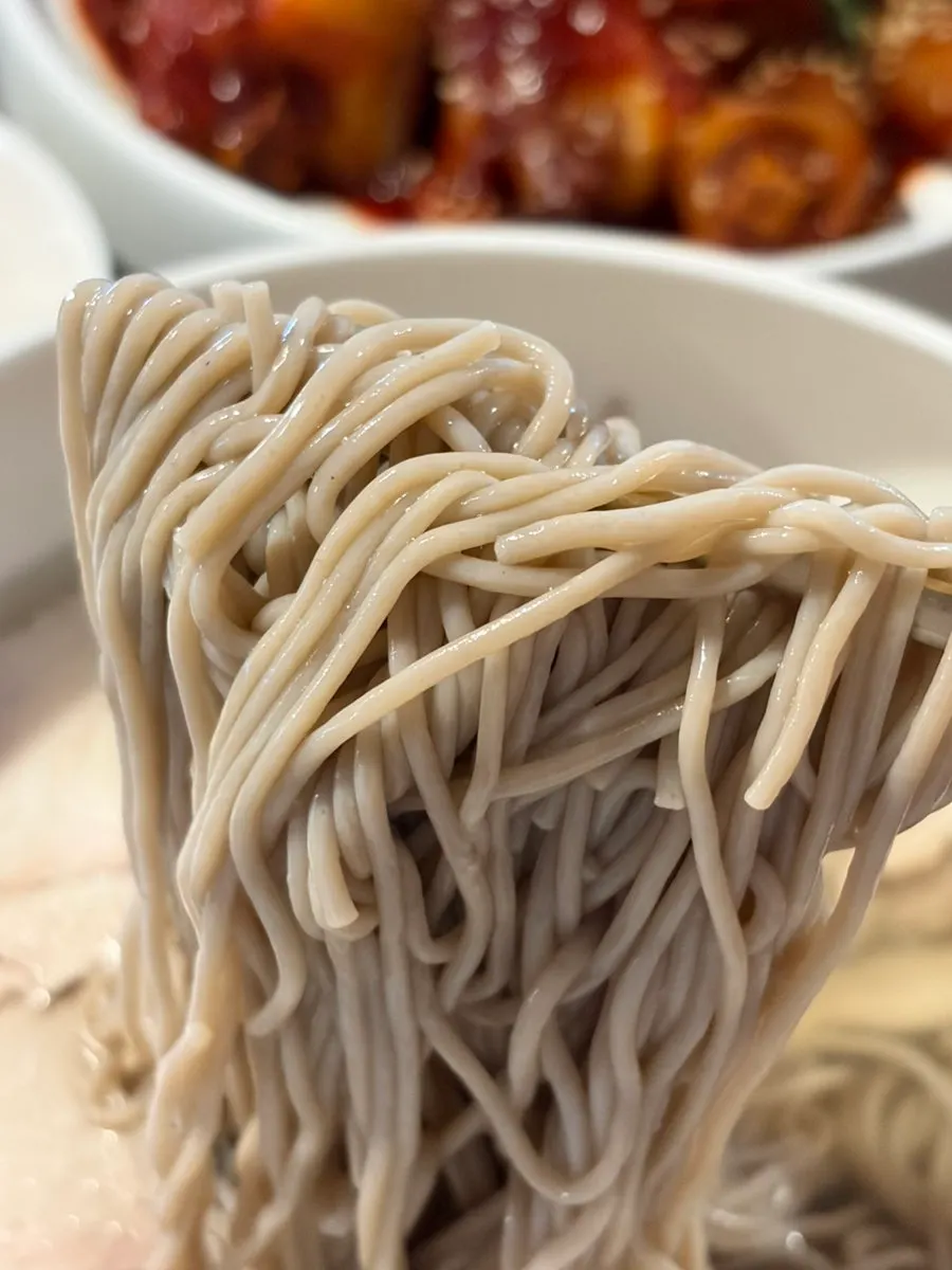 Mi naengmyeon diangkat menggunakan penyepit