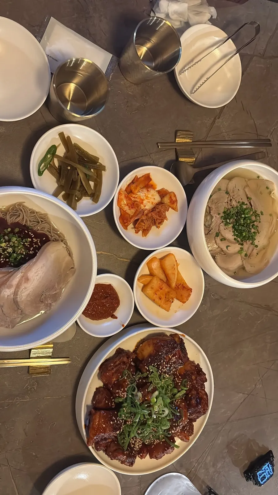 Full table spread of Anok's pork tail jjim topped with scallions and gomtang