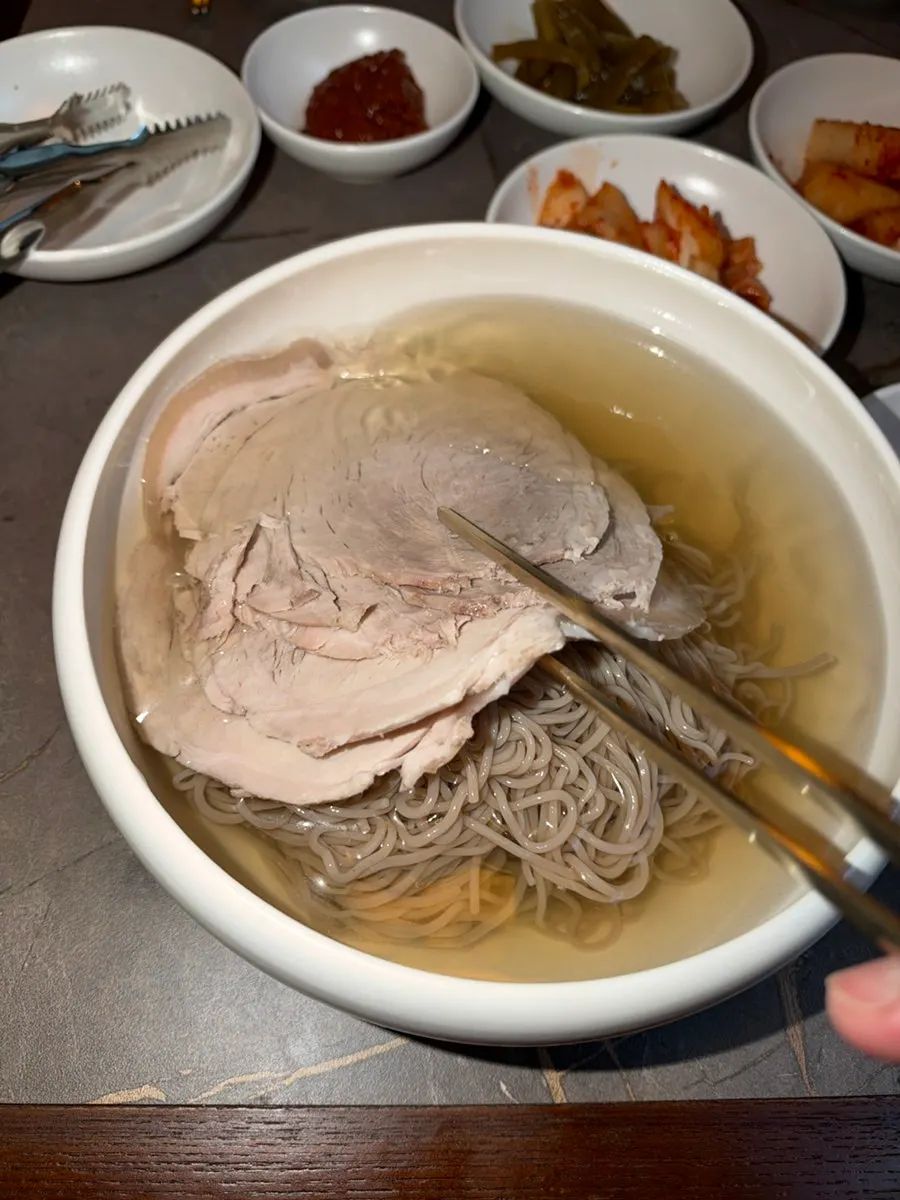 Buckwheat naengmyeon noodles lifted with chopsticks