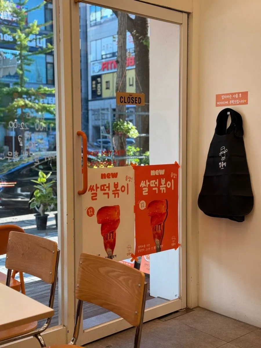 쌀떡볶이 포스터가 붙은 매장 입구와 앞치마