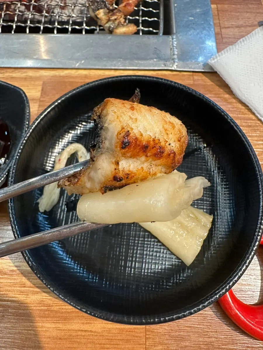 A piece of eel dipped in sauce and paired with ginger
