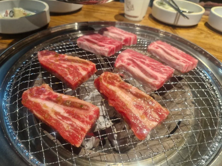 Raw LA galbi turning golden brown on the grill