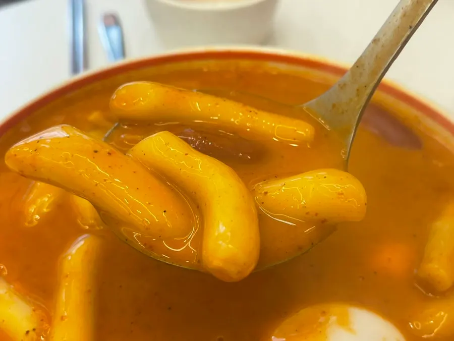 3 servings of rose tteokbokki piled high in a naengmyeon bowl