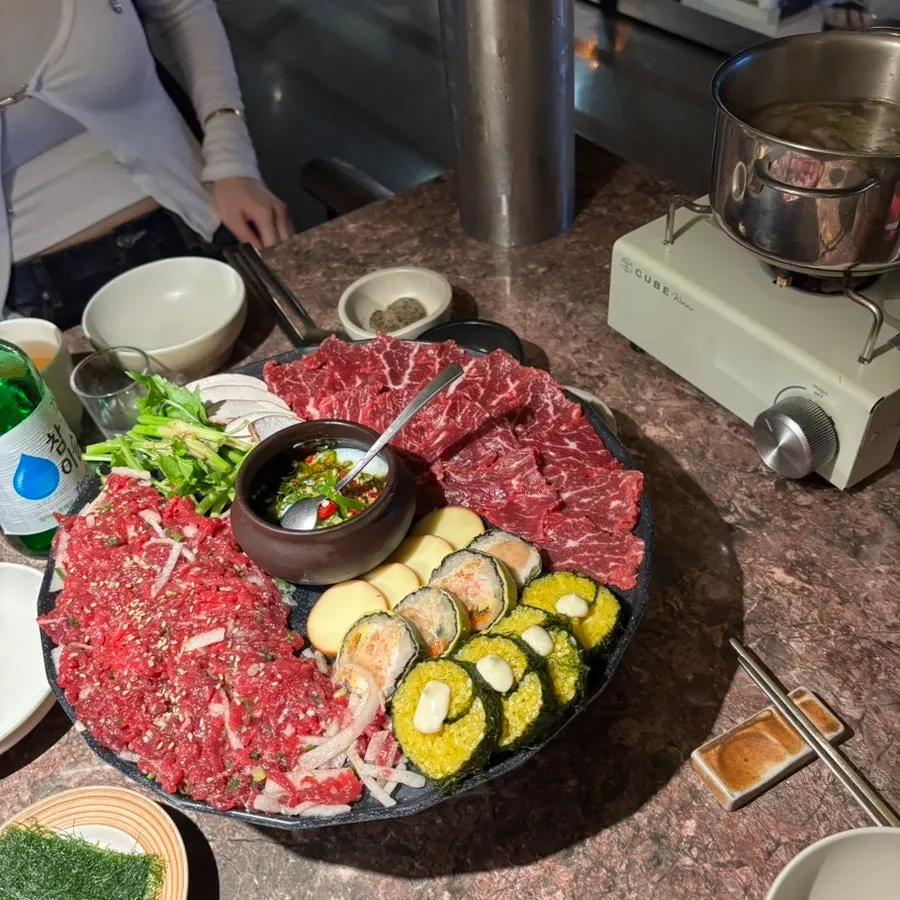 Beef radish soup simmering on a burner next to soju glasses