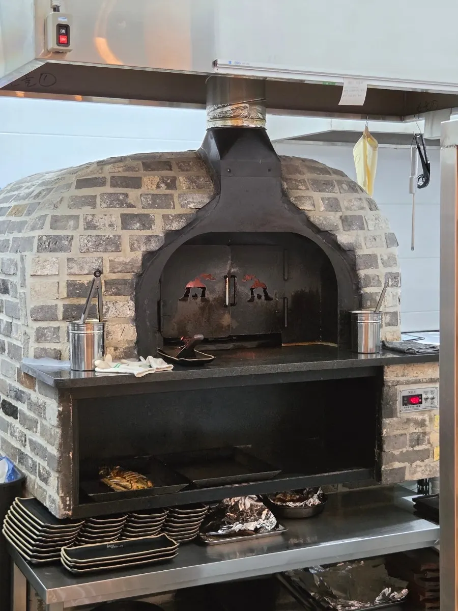 Large wood-fired oven for grilling fish, visible from the kitchen