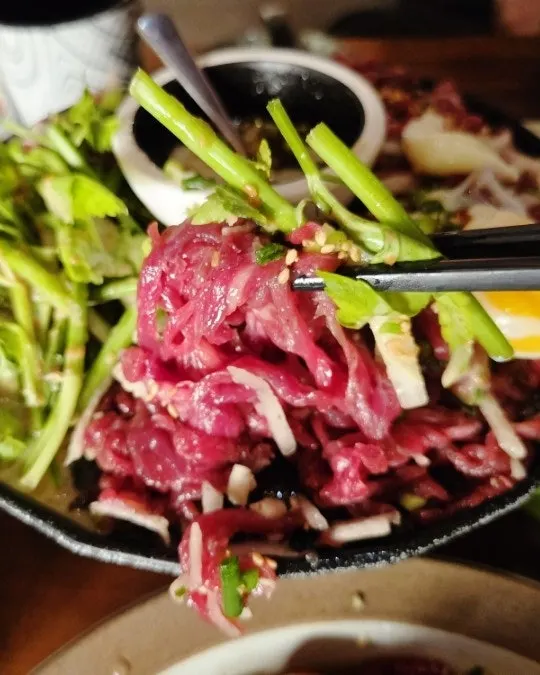 Bàn ăn với yukhoe và pasta bày cùng nhau
