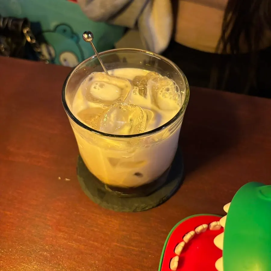 A gin tonic topped with lime and a Kahlua milk