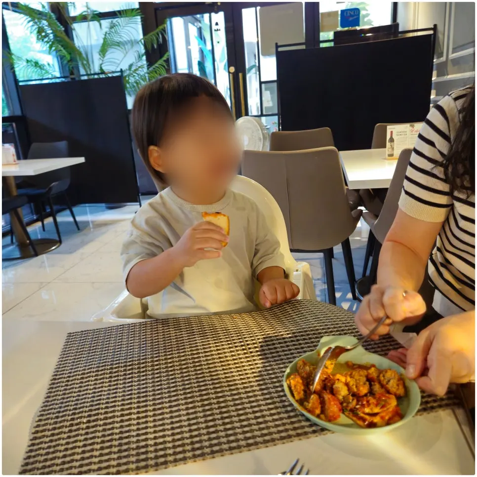 A two-year-old baby eating in a baby chair
