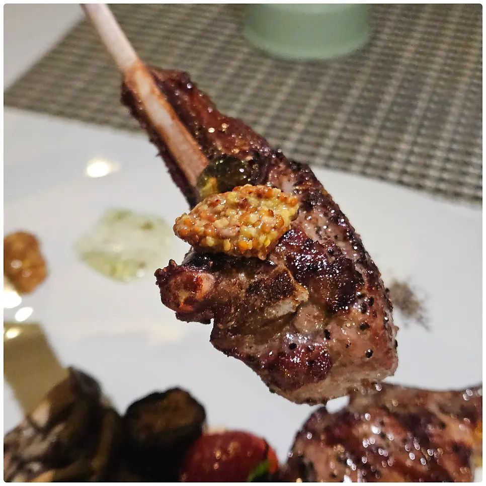 A piece of lamb chop topped with whole grain mustard