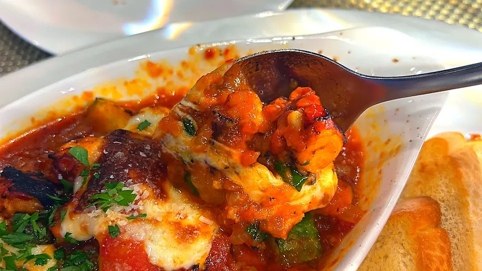 A spoonful of ratatouille with a piece of octopus