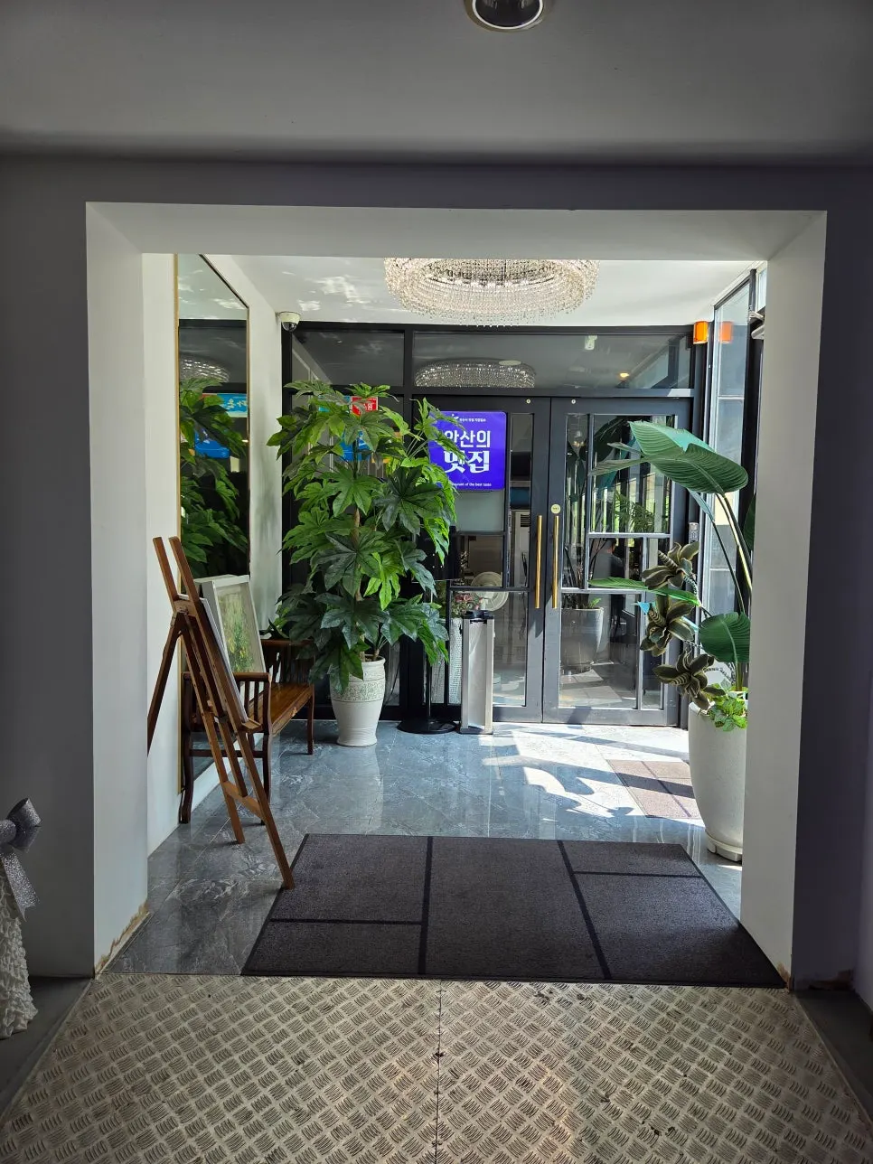 Restaurant entrance decorated with a chandelier and large plants