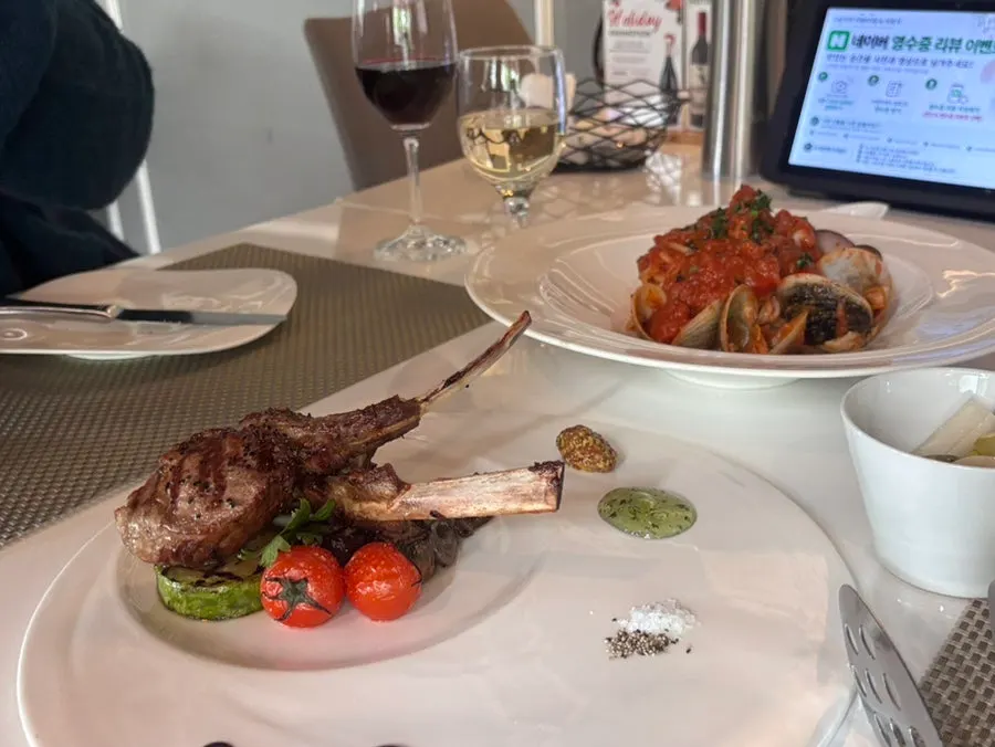 Full table spread with wine, lamb chop steak and pasta
