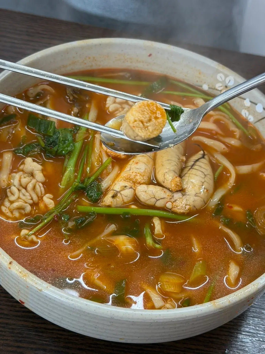 A bowl of Todamok chicken kalguksu with noodles lifted up