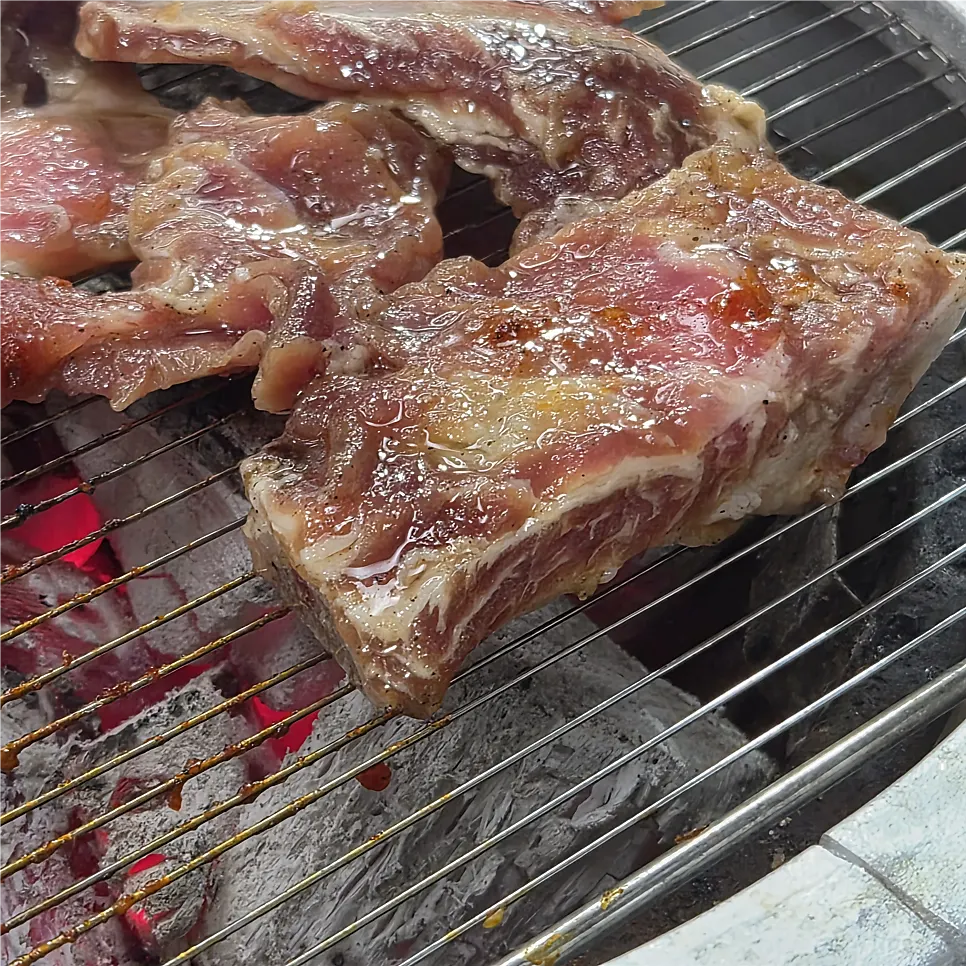 Pork ribs cooking over strong charcoal heat