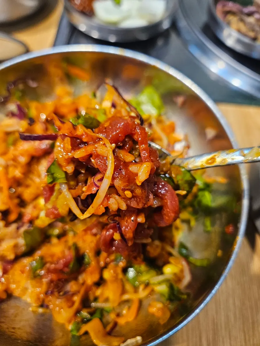 A bite of yukhoe bibimbap mixed with vegetables