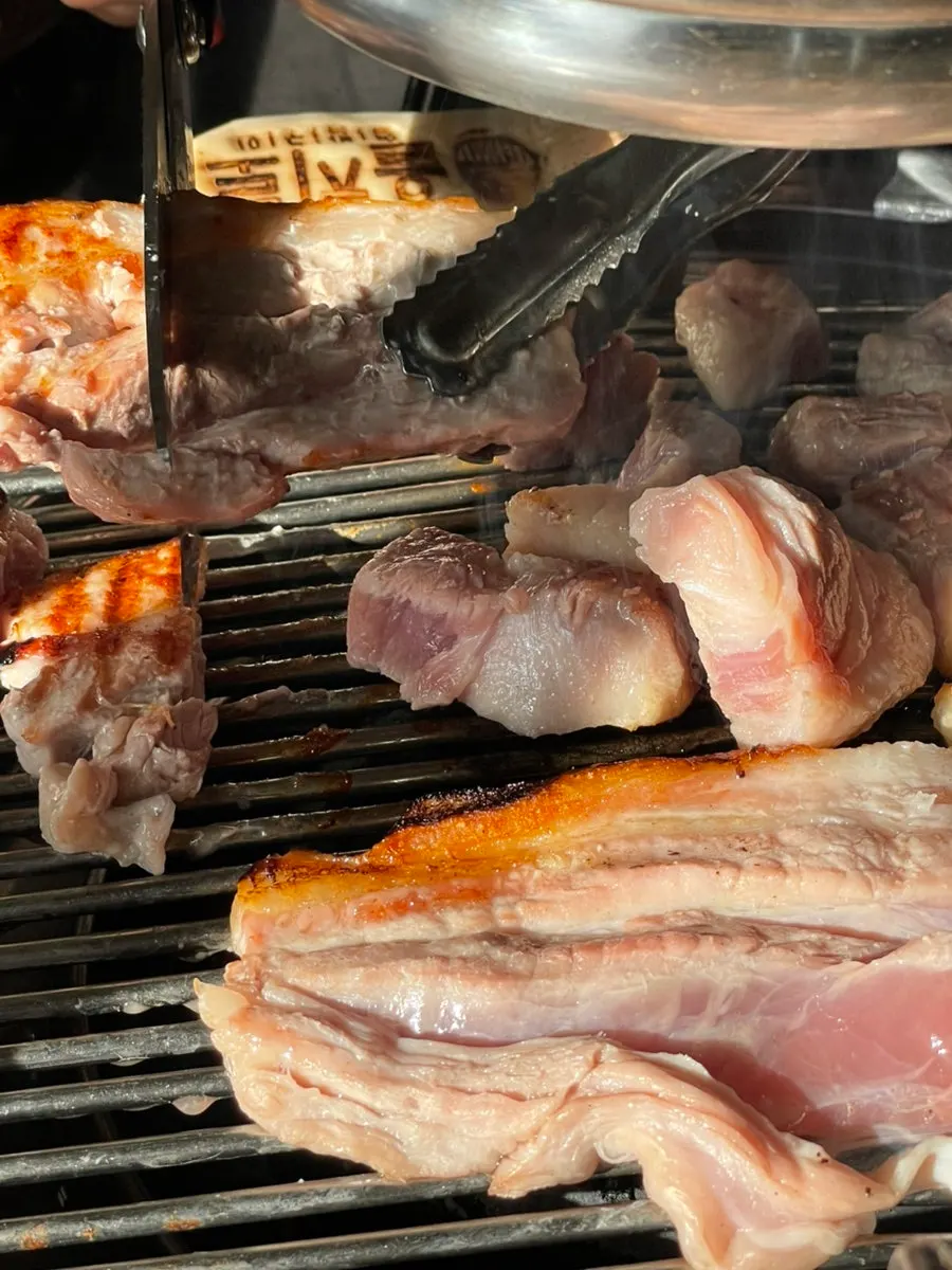 Thick pork belly grilling to a nutty finish