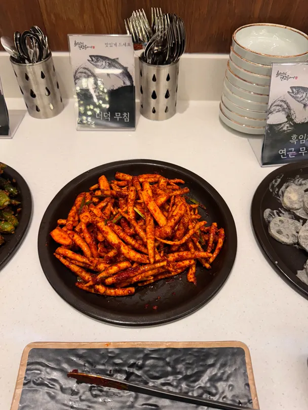 Plate of chonggak kimchi and deodeok muchim and other self-bar side dishes