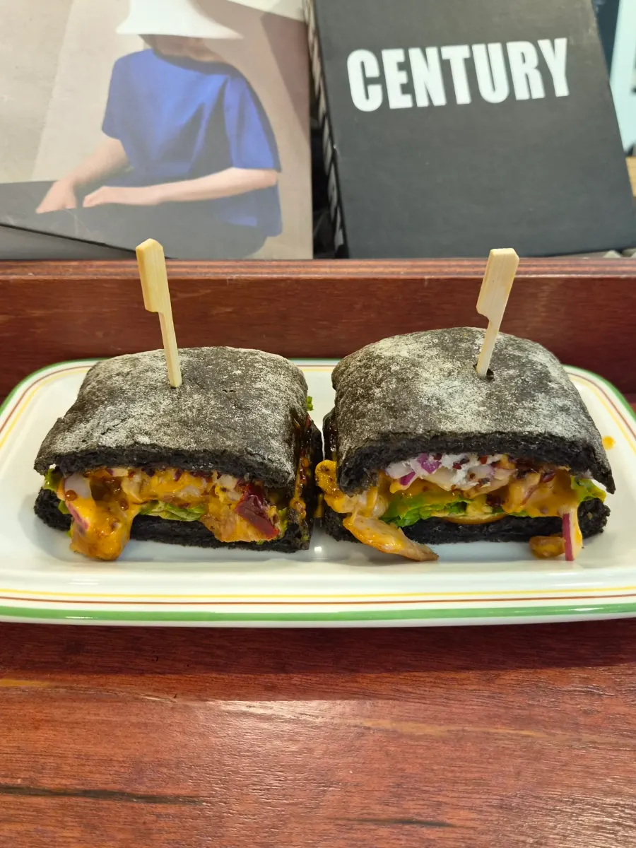 Plate with the squid-ink bread spicy chicken sandwich