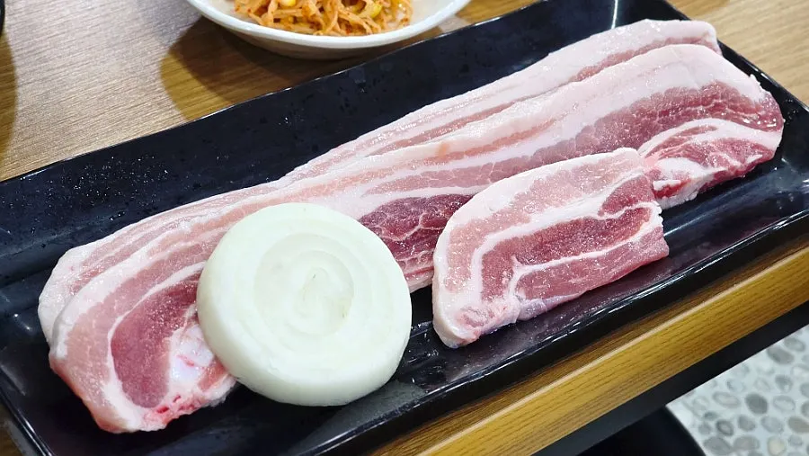 Raw pork belly served alongside the set-up grill