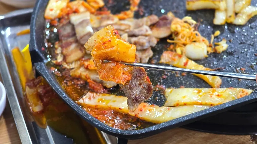 Kimchi sizzling in pork belly fat on the grill