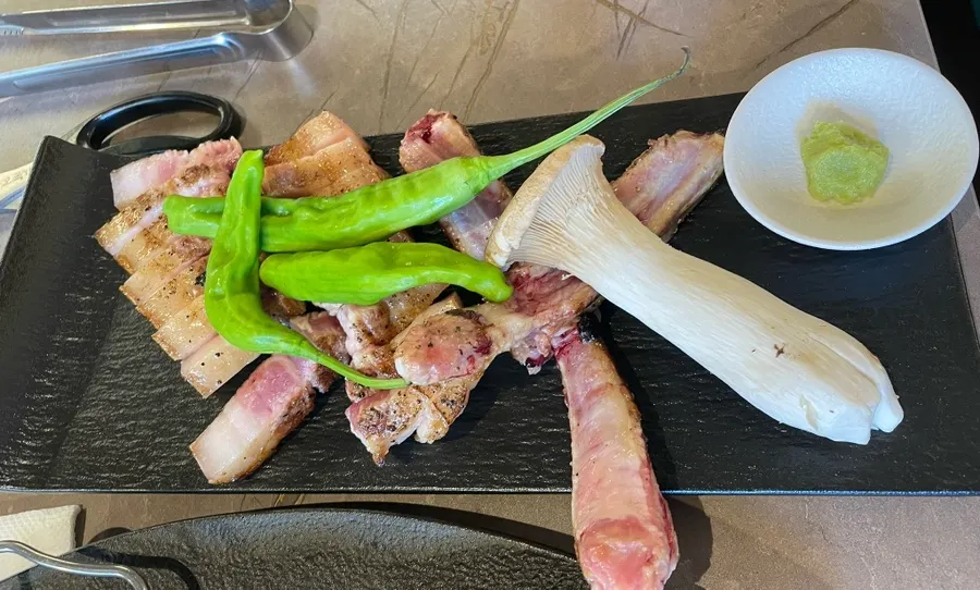 Pre-grilled bone pork belly cooking on the grill