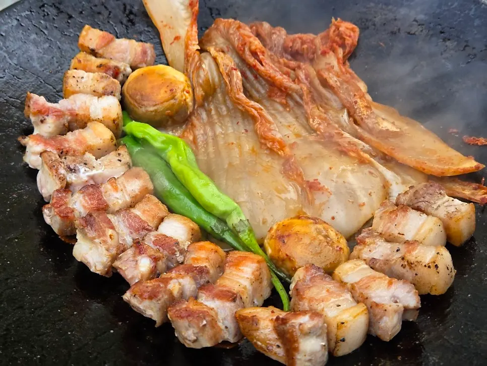 Pre-seared pork belly being grilled again on the griddle