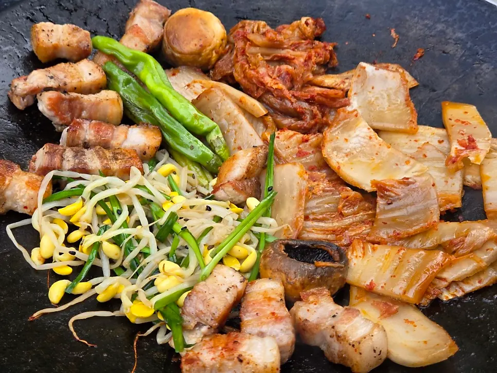 Griddle with kimchi and mushrooms grilled alongside the meat