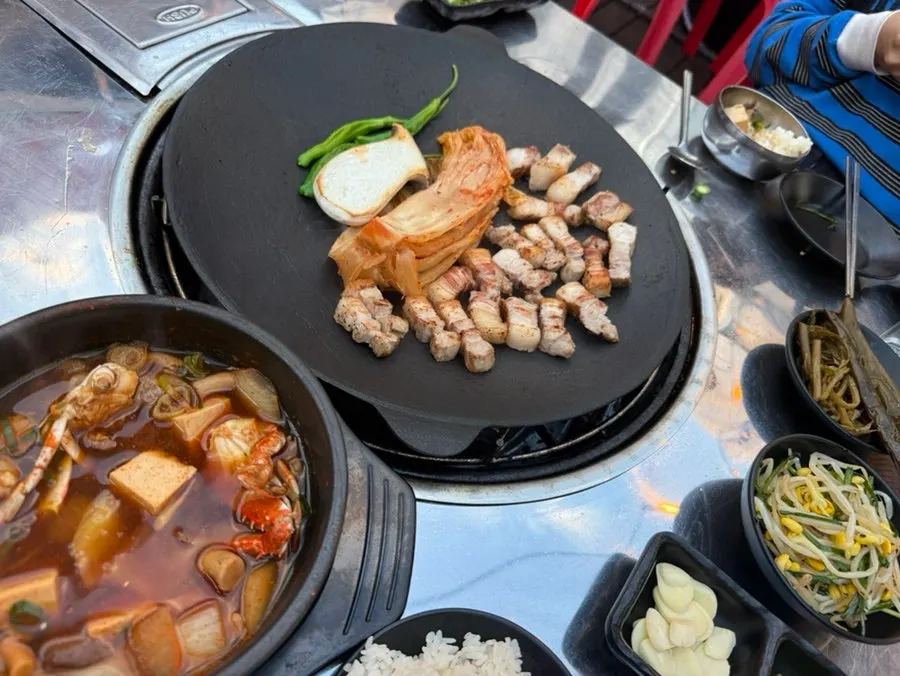 Pre-seared pork belly and whole kimchi grilling on the cauldron-lid griddle