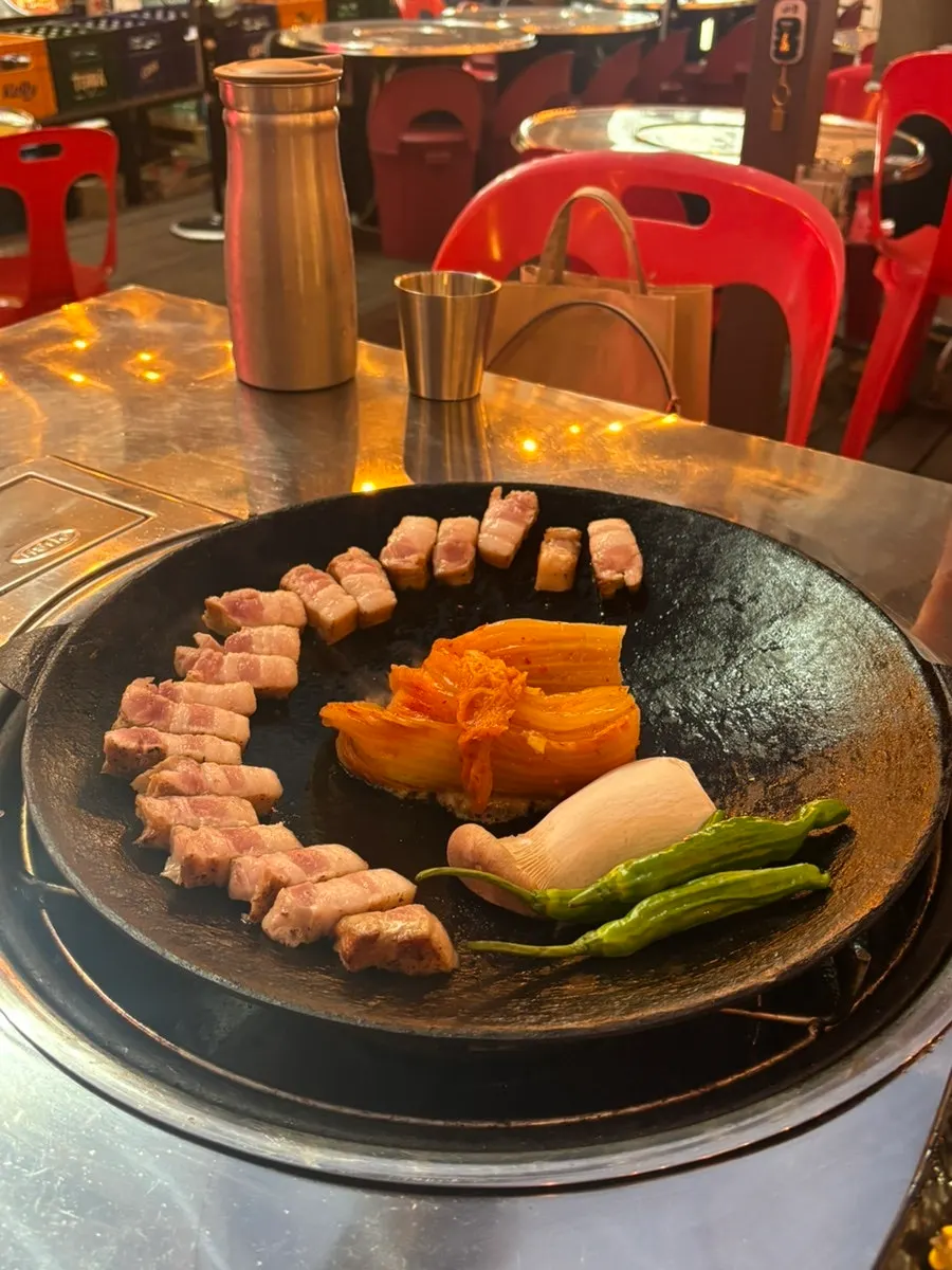 Preheated camping griddle with two servings of pre-seared pork belly