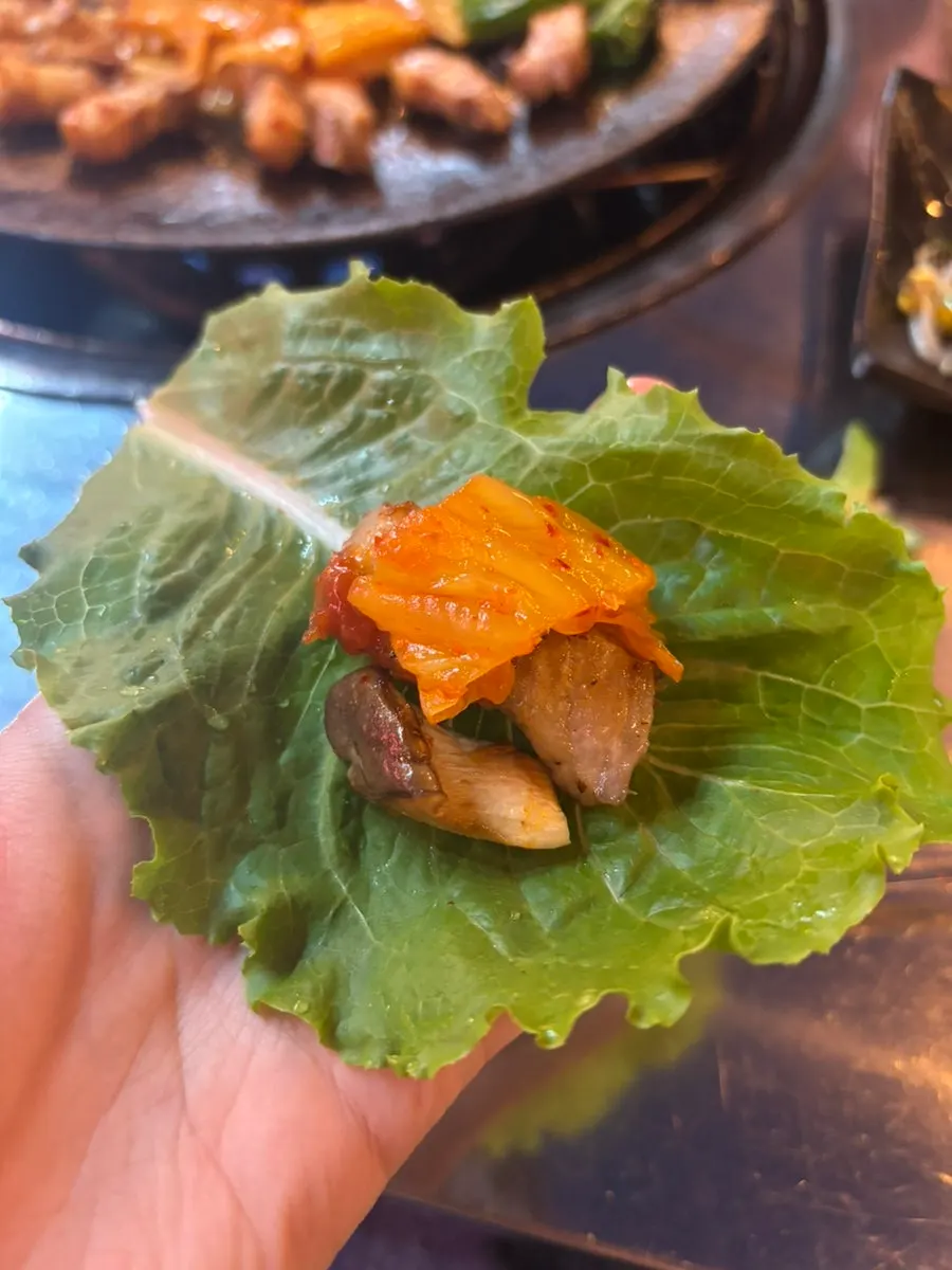 A piece of Chobeoljip's pork belly wrapped in aged kimchi