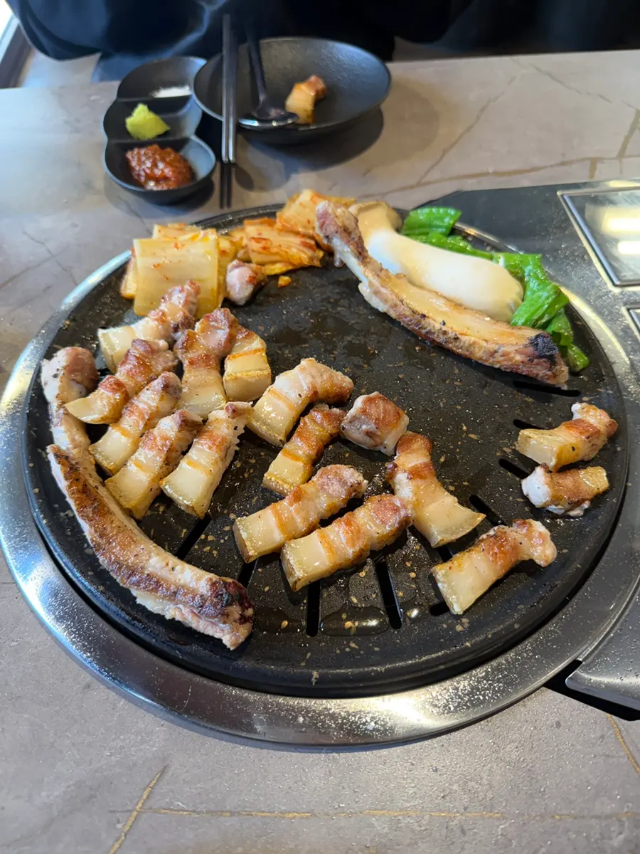 Par-cooked bone samgyeopsal finishing on the table grill