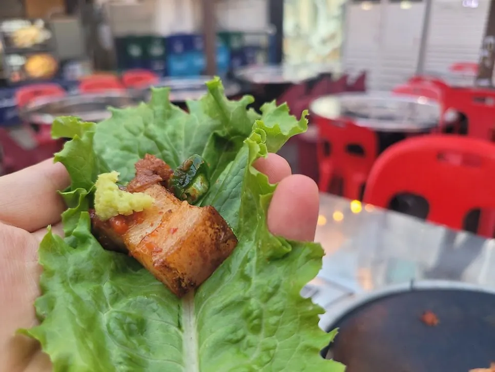 A pork ssam wrap topped with seasoned bean sprouts and kimchi