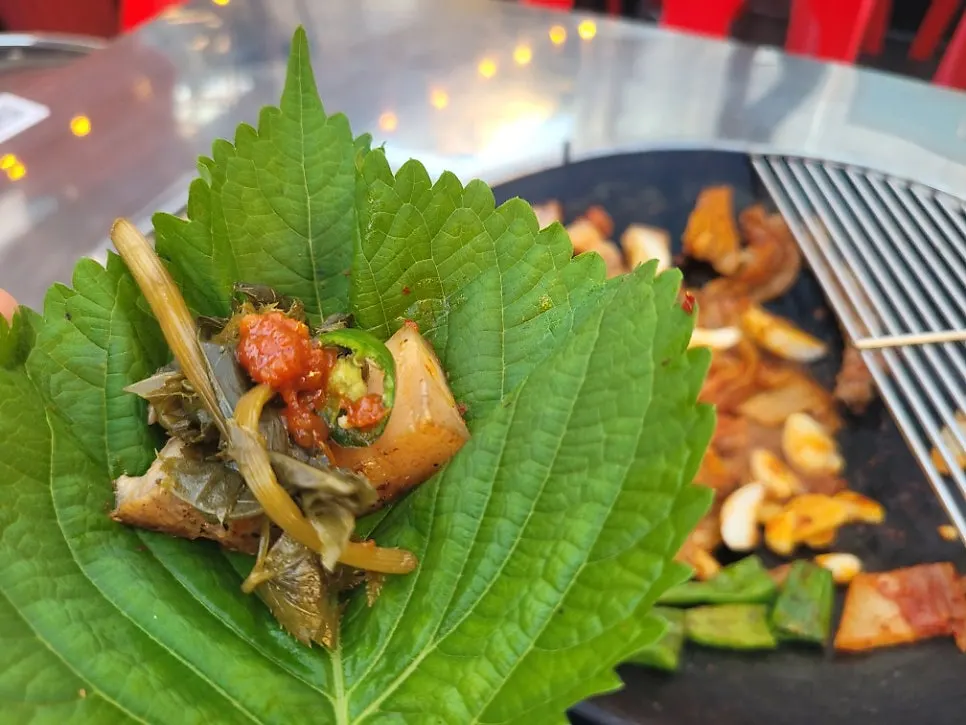 A perilla-leaf ssam wrap with pickles and peppers