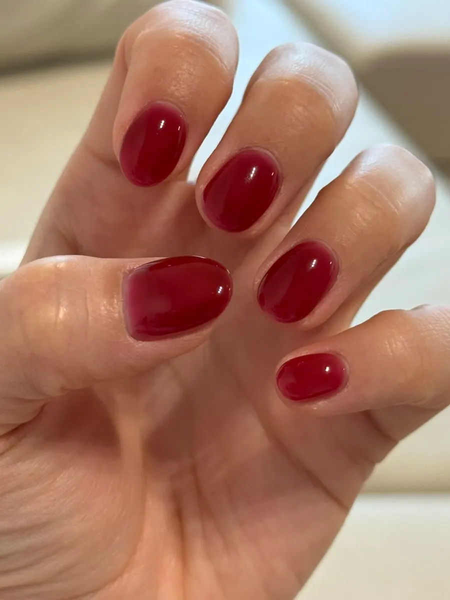 Cherry red gel nails viewed under indoor lighting