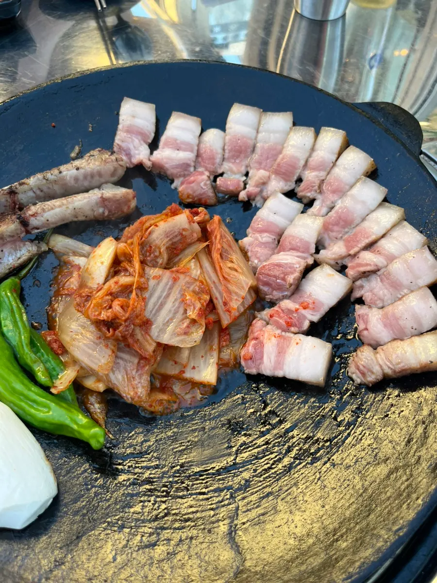 솥뚜껑에서 구워지는 뼈삼겹과 김치
