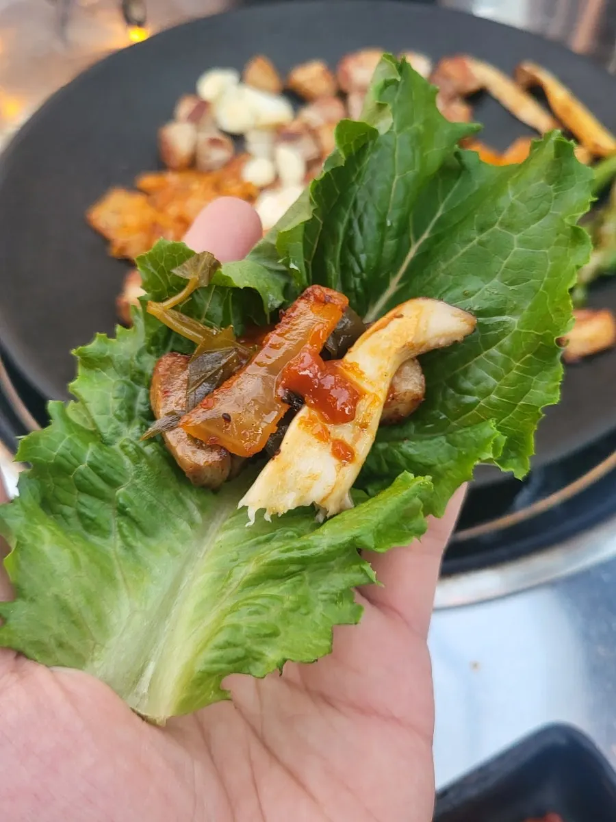 Griddle with pork belly and kimchi nearly done cooking