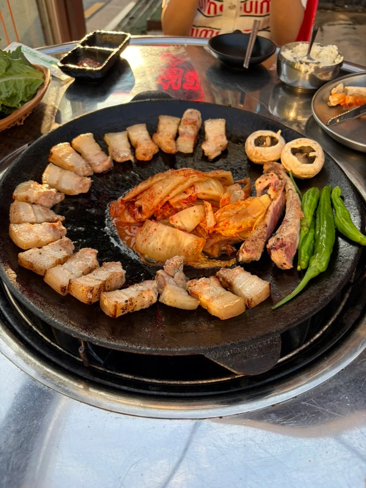 Bone-in pork belly and side dishes cooking on the grill