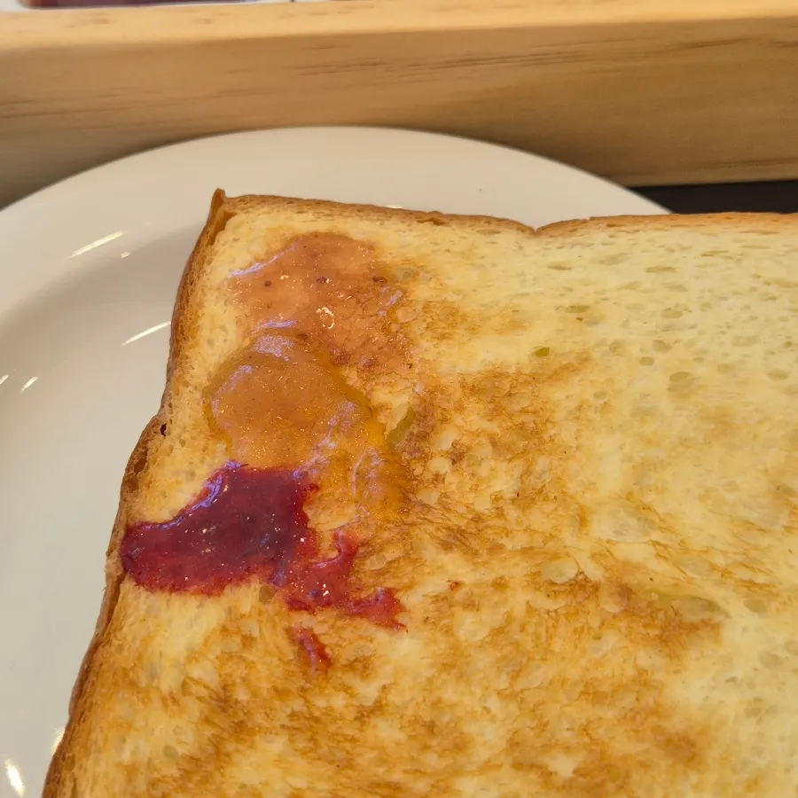A slice of warm toast spread with jam
