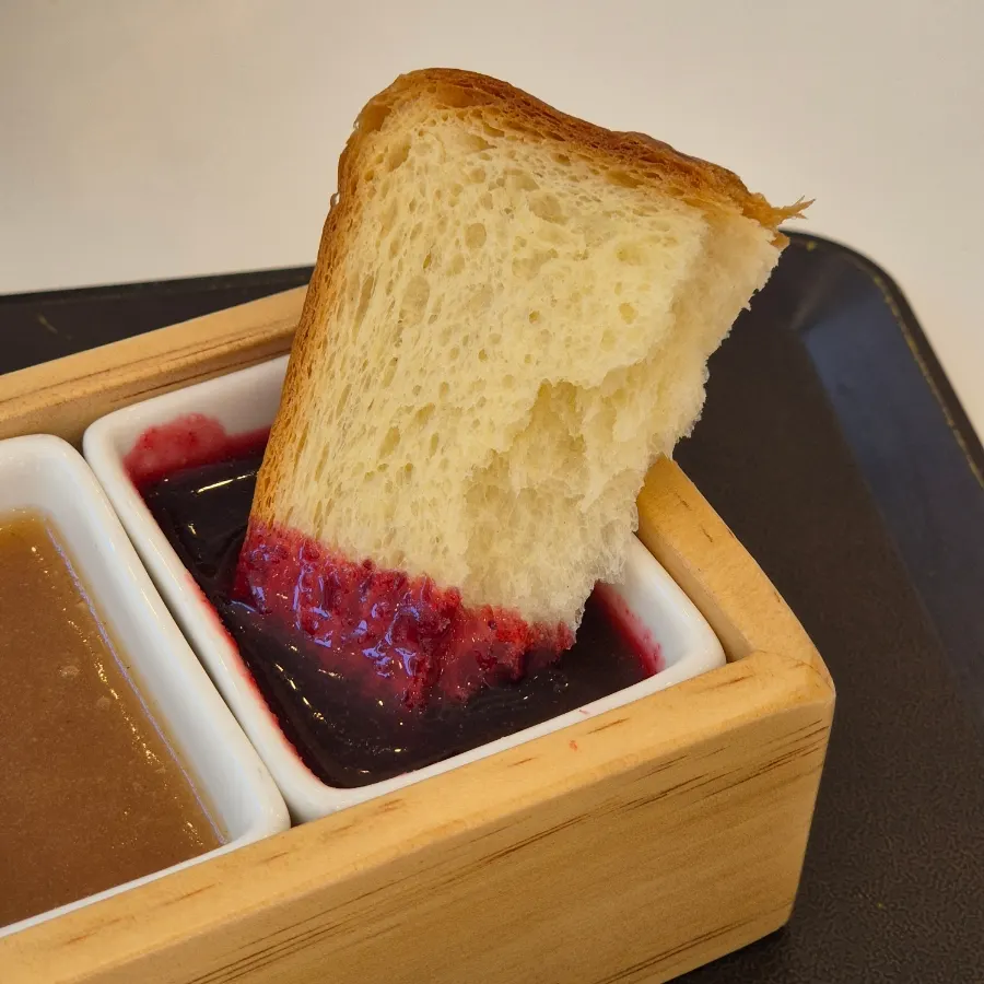 A piece of bread dipped into cherry jam