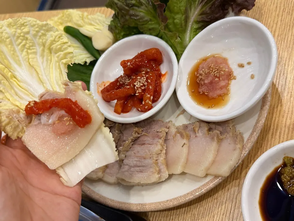 A piece of bossam topped with radish kimchi