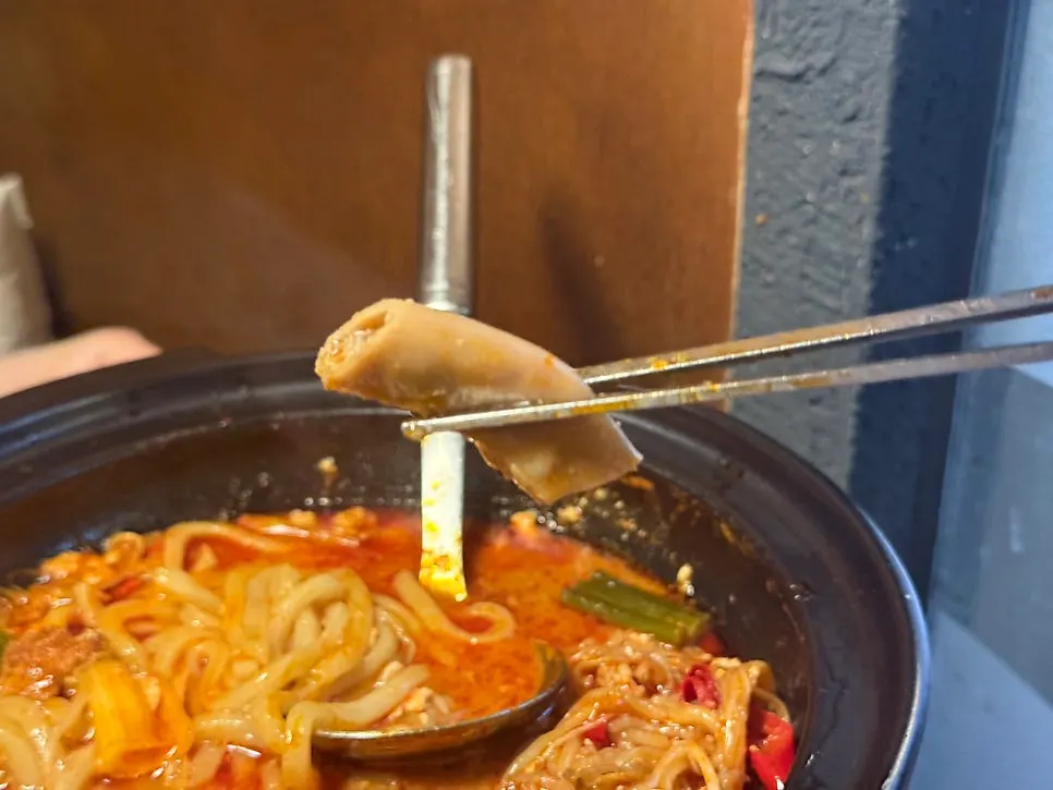 Udon noodles lifted from the spicy hot pot broth