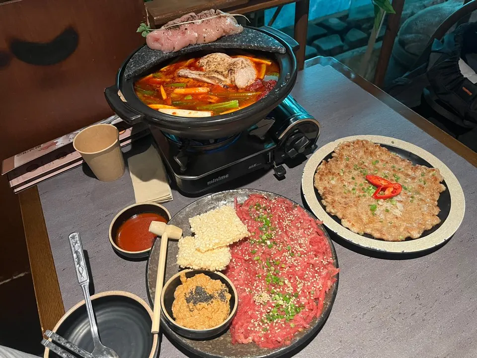 Table spread of chicken hot pot, hoe, and yukjeon with makgeolli