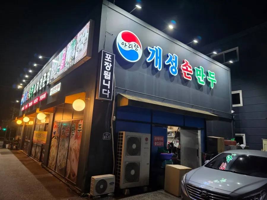 밤에 환하게 켜진 아리랑 개성손만두 식사점 간판