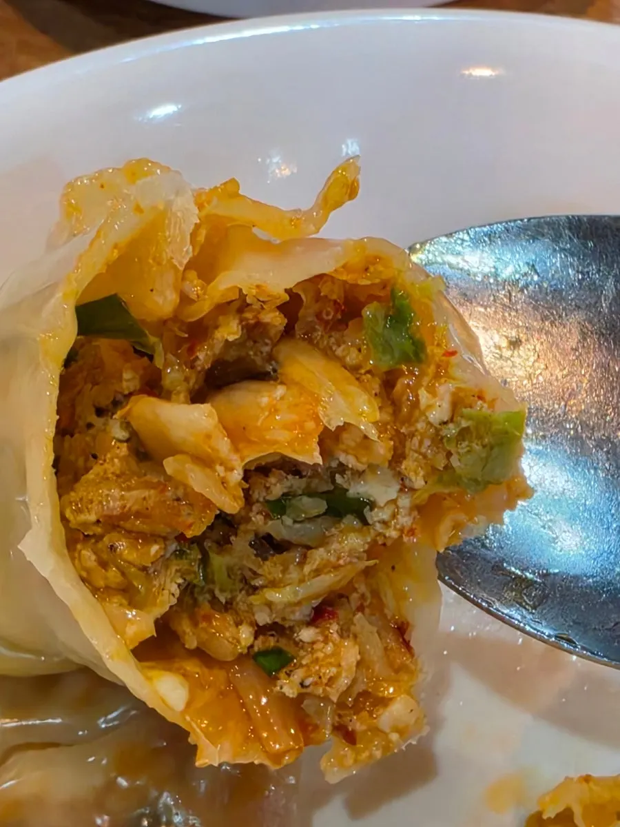 Bite of kimchi mandu dipped in soy sauce