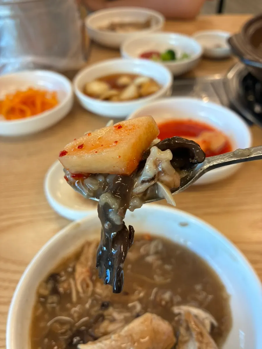 A bowl of broth topped with scorched rice and neungi mushroom