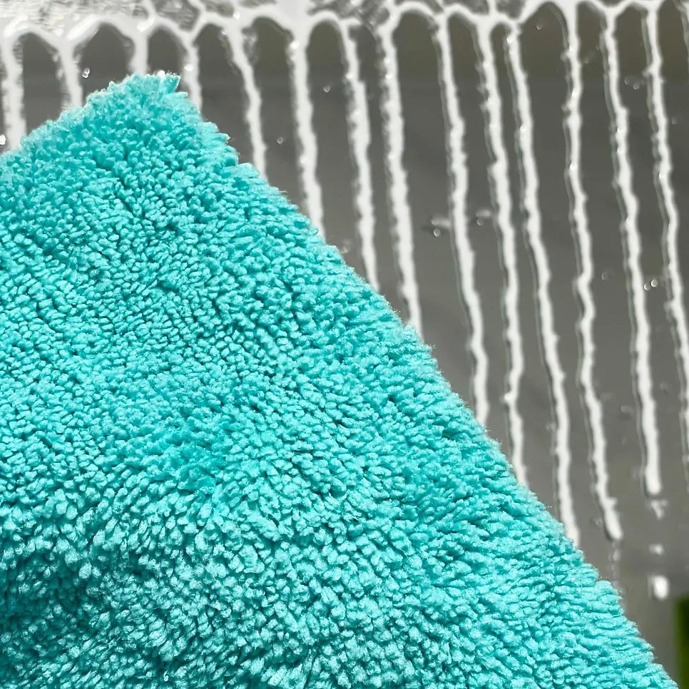 Wiping water stains from a bathroom mirror with oil-film remover