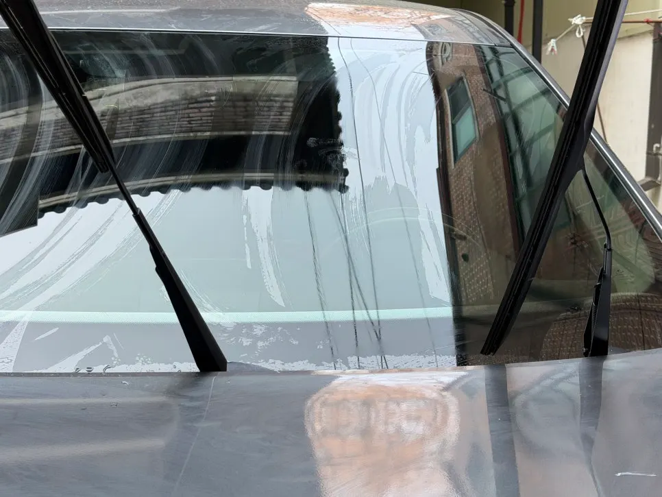 Car undergoing oil film removal on its front and rear glass